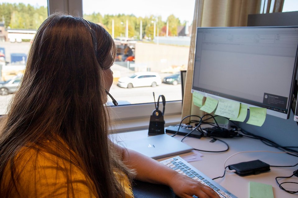 Bild: En kvinna sitter framför en dator med ett headset.