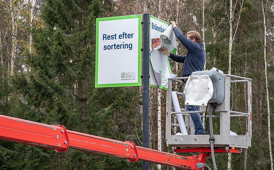 Bild: En montör klistrar en dekal med texten Rest efter sortering över en Brännbart-skylt